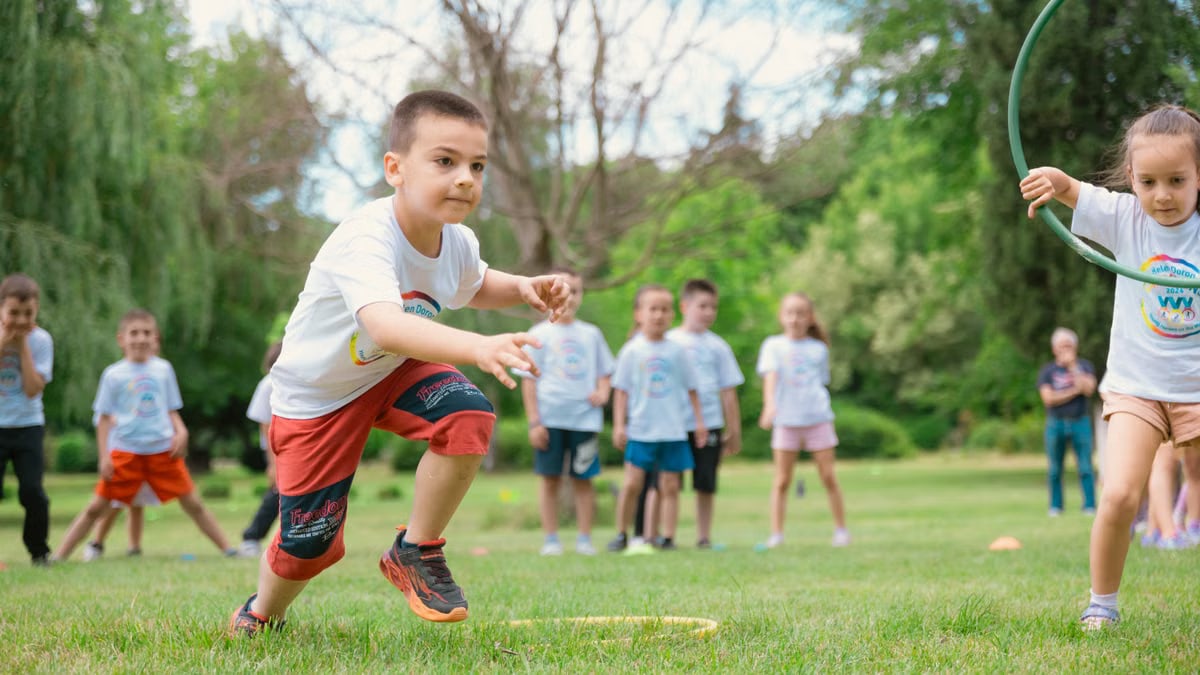A group of children actively playing with hula hoops on a bright summer day in the park.